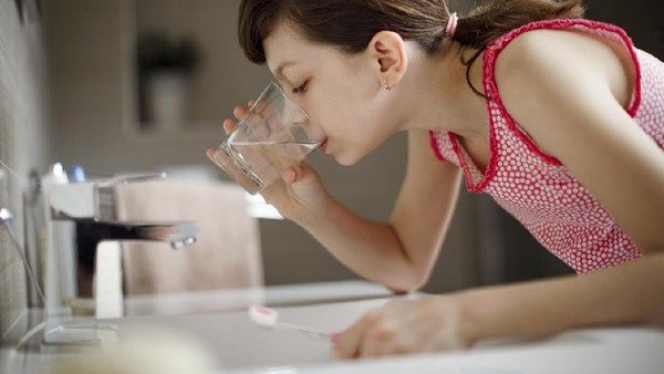 Teenage girl rinsing her mouth with glass of water