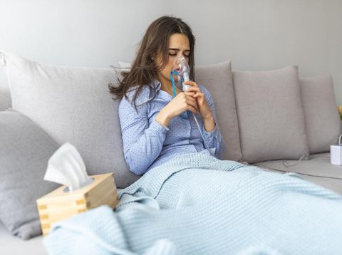Woman holding a mask nebulizer inhaling fumes spray the medication into your lungs sick patient. Self-treatment of the respiratory tract using inhalation nebulizer