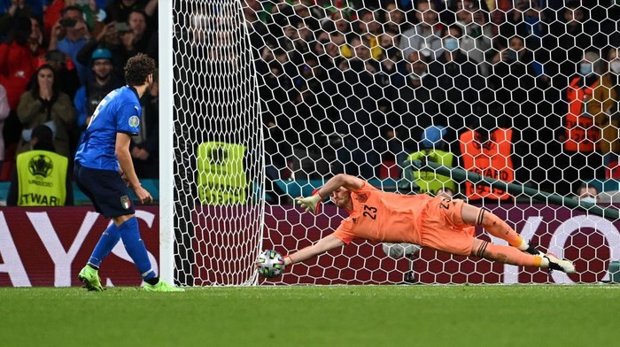 LONDON, ENGLAND - JULY 06: Unai Simon of Spain saves the first penalty from Manuel Locatelli of Italy during a penalty shoot out during the UEFA Euro 2020 Championship Semi-final match between Italy and Spain at Wembley Stadium on July 06, 2021 in London, England. (Photo by Andy Rain - Pool/Getty Images)