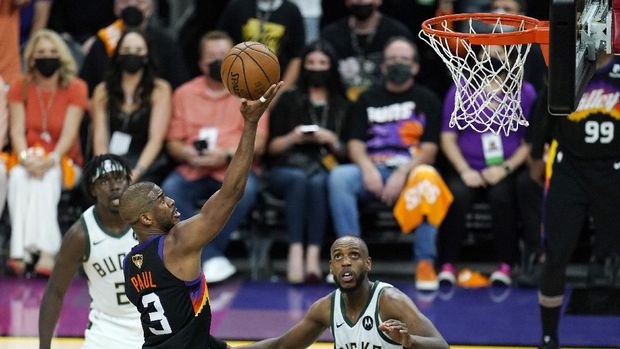 Phoenix Suns guard Chris Paul (3) scores as Milwaukee Bucks forward Khris Middleton (22) and Bucks guard Jrue Holiday, left, look on during the second half of Game 1 of basketball's NBA Finals, Tuesday, July 6, 2021, in Phoenix. (AP Photo/Ross D. Franklin)
