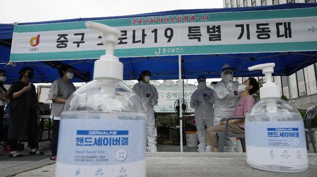 A medical worker takes a nasal sample from a woman at a coronavirus testing site in Seoul, South Korea, Thursday, July 8, 2021. South Korea has reported its biggest daily jump in coronavirus cases since the start of the pandemic as long lines snake around testing stations in the capital, where the virus has accelerated following months of complacency. The banner in the background reads: 