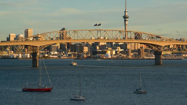 Jembatan Auckland Harbour di Auckland, Selandia Baru The Auckland Harbour Bridge with the CBD in the background, cast in golden light by the late setting sun.