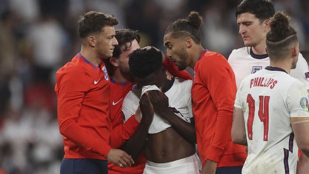 England players comfort teammate Bukayo Saka after he failed to score a penalty during a penalty shootout after extra time during of the Euro 2020 soccer championship final match between England and Italy at Wembley stadium in London, Sunday, July 11, 2021. (Carl Recine/Pool Photo via AP)