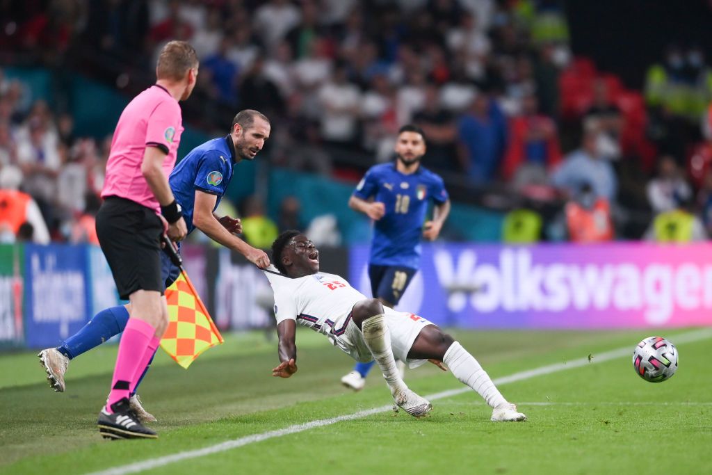 LONDON, ENGLAND - JULY 11: Bukayo Saka of England is fouled by Giorgio Chiellini of Italy during the UEFA Euro 2020 Championship Final between Italy and England at Wembley Stadium on July 11, 2021 in London, England. (Photo by Laurence Griffiths/Getty Images)