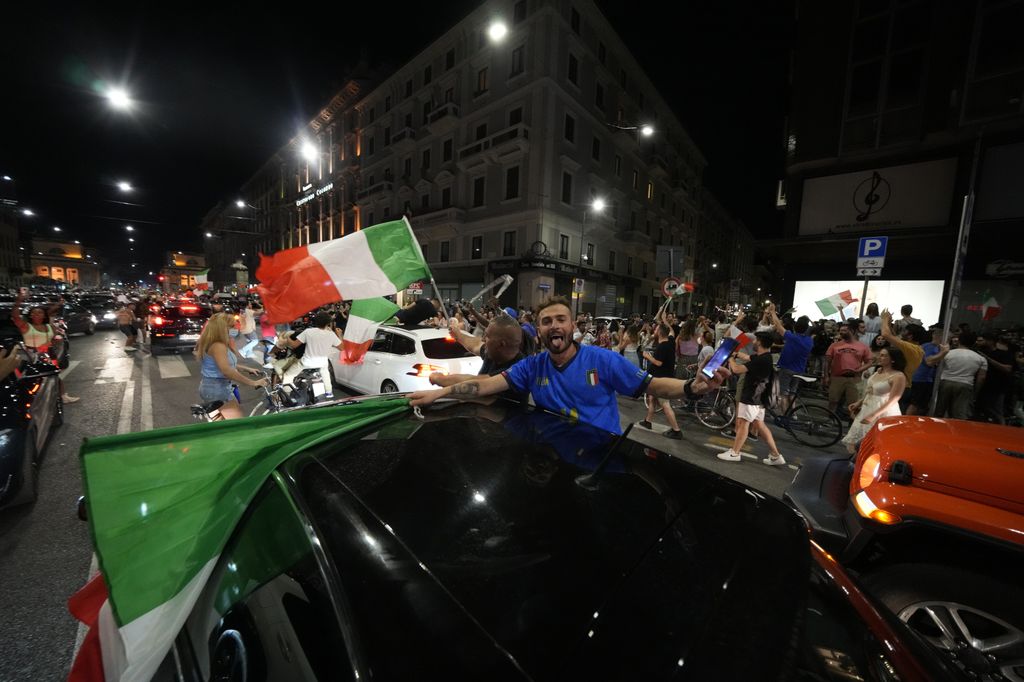 Italy's fans celebrate in Milan, Italy, Monday, July 12, 2021, after Italy beat England to win the Euro 2020 soccer championships in a final played at Wembley stadium in London. Italy beat England 3-2 in a penalty shootout after a 1-1 draw. (AP Photo/Luca Bruno)