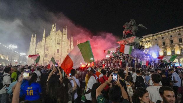Italy's fans celebrate in front of the Duomo cathedral in Milan, Monday, July 12, 2021, after Italy beat England to win the Euro 2020 soccer championships in a final played at Wembley stadium in London. Italy beat England 3-2 in a penalty shootout after a 1-1 draw. (AP Photo/Luca Bruno)