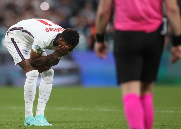 Englands forward Marcus Rashford (L) reacts after failing to score in the penalty shootout during the UEFA EURO 2020 final football match between Italy and England at the Wembley Stadium in London on July 11, 2021. (Photo by CARL RECINE / POOL / AFP)