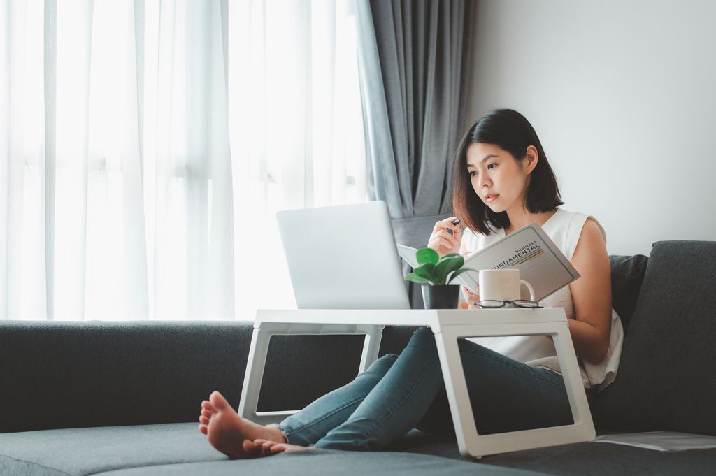 Asian woman working with laptop notebook at home on sofa