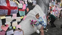 Seorang anak perempuan meletakkan bunga di depan mural Rashford yang sebelumnya menjadi sasaran aksi vandalisme dan serangan rasial.