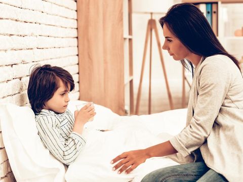 Mother Giving Medicine to Sick Son Lying Bed. Caring Mom Giving Sick Boy Pills. Worried Mother Giving Glass of Water to Ill Kid. Hospital Concept. Healthy Concept. Parent Concept.