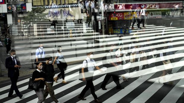 Nyalang Edisi 17 Juli 2021 Commuters are reflected in a bus window as they cross the street Thursday, July 15, 2021, in Tokyo. The pandemic-delayed 2020 Summer Olympics open on July 23 without spectators at most venues. (AP Photo/Jae C. Hong)