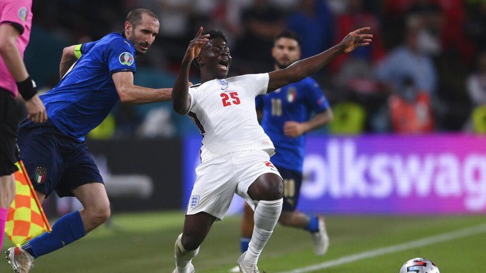 Italys Giorgio Chiellini, left, stops Englands Bukayo Saka during the Euro 2020 soccer final match between England and Italy at Wembley stadium in London, Sunday, July 11, 2021. (Laurence Griffiths/Pool via AP)