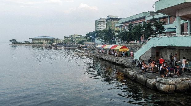 Wonsan, North Korea - 1 August 2014. People hanging out on a concrete terrace by the sea