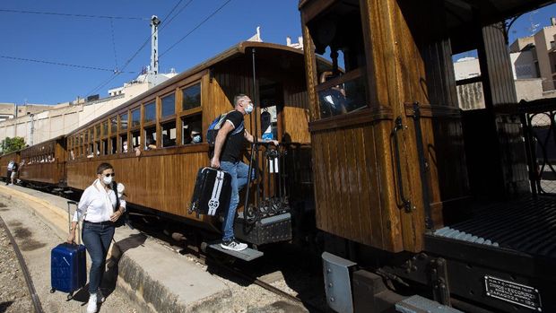 Jelajah Rute Tertua Kereta Api Spanyol Passengers get on the Palma-Soller train before beginning its journey in Palma de Mallorca in the Spanish Balearic Islands on July 14, 2021. - Inaugurated in 1912, the Palma-Soller railway line is one of the oldest routes still in operation in Spain. The wagons and locomotives retain their original designs, with maintenance and repairs carried out in the railway's own workshops, respecting the initial model. (Photo by JAIME REINA / AFP)