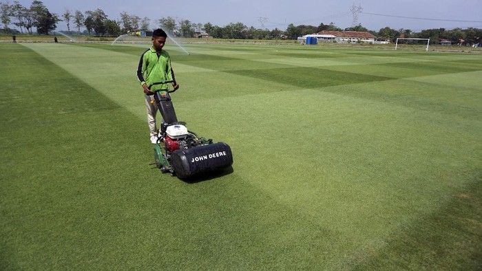 Pekerja memotong rumput lapangan sepak bola menggunakan mesin di Lapangan Desa Purwodadi, Sragi, Kabupaten Pekalongan, Jawa Tengah, Senin (19/7/2021). Pemerintah desa setempat bekerja sama dengan pihak swasta memanfaatkan tanah kas desa (TKD) di Lapangan Desa Purwodadi seluas tiga hektare menjadi lapangan sepak bola berstandar FIFA dengan sistem kerja sama Bangun Guna Serah sebesar Rp5,5 miliar. ANTARA FOTO/Harviyan Perdana Putra/aww.