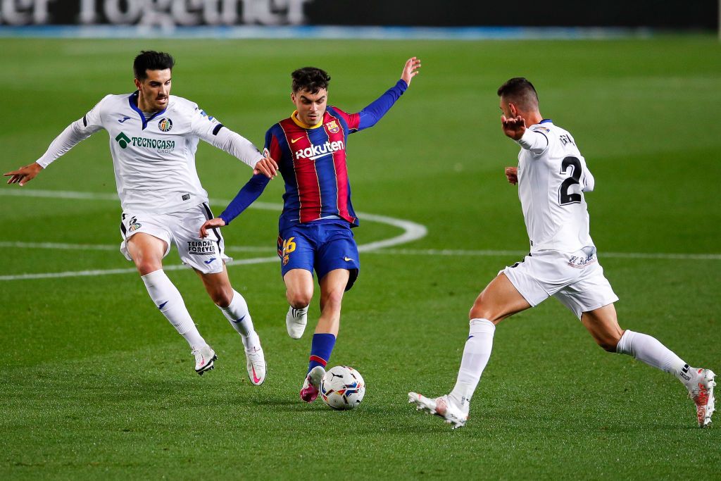 BARCELONA, SPAIN - APRIL 22: Pedro 'Pedri' Gonzalez  of FC Barcelona is tackled by Chema Rodríguez of Getafe CF during the La Liga Santander match between FC Barcelona and Getafe CF at Camp Nou on April 22, 2021 in Barcelona, Spain. Sporting stadiums around the UK remain under strict restrictions due to the Coronavirus Pandemic as Government social distancing laws prohibit fans inside venues resulting in games being played behind closed doors. (Photo by Eric Alonso/Getty Images)