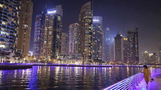 A woman walks by the waterline at the Dubai Marina in the United Arab Emirates, on February 16, 2021. (Photo by Giuseppe CACACE / AFP)