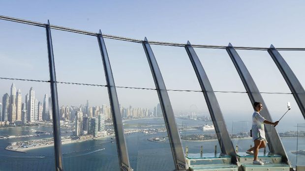 Menikmati Dubai, Kota Termahal di Timur Tengah A woman takes a selfie photograph with the Dubai Marina behind her at The View at the Palm observation deck in Dubai, United Arab Emirates, Monday, July 19, 2021. (AP Photo/Jon Gambrell)