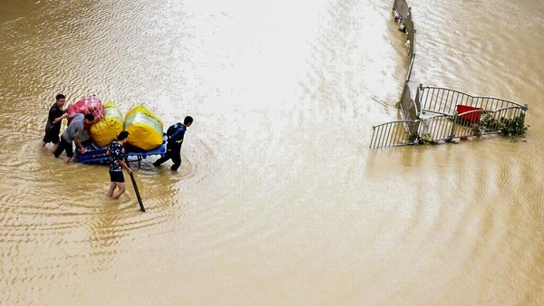 Foto: Dahsyatnya Banjir di China In this photo released by Xinhua News Agency, residents move their belongings across a flooded street in Zhengzhou in central Chinas Henan province on Wednesday, July 21, 2021. Chinas military has blasted a dam to release floodwaters threatening one of its most heavily populated provinces, as the death toll in widespread flooding rose to more than two dozens. (Zhu Xiang/Xinhua via AP)