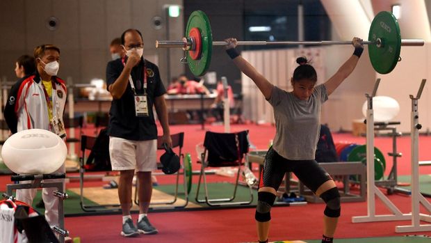 Lifter putri Indonesia Windy Cantika Aisah (kanan) melakukan angkatan saat sesi latihan disaksikan CdM Kontingen Indonesia Rosan Roeslani (tengah) dan Kepala Pelatih Angkat Besi Dirja Wihardja (kiri) di Arena Angkat Besi Olimpiade Tokyo 2020, Tokyo International Forum, Tokyo, Jepang, Kamis (22/7/2021). Cantika akan bertanding dalam kelas 49 Kg putri Olimpiade Tokyo 2020 pada Sabtu 24 Juli 2021. ANTARA FOTO/Sigid Kurniawan/rwa.