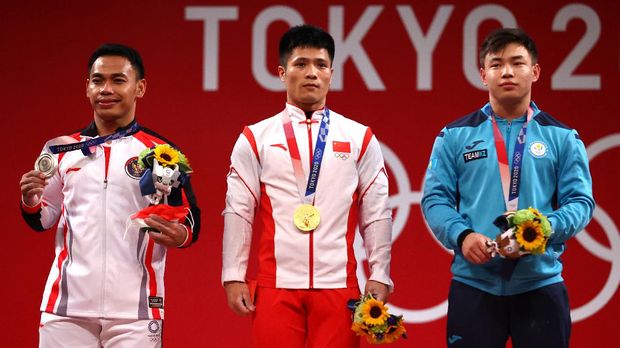 Tokyo 2020 Olympics - Weightlifting - Men's 61kg - Medal Ceremony - Tokyo International Forum, Tokyo, Japan - July 25, 2021. Gold medalist Li Fabin of China, silver medalist Eko Yuli Irawan of Indonesia and bronze medalist Igor Son of Kazakhstan react. REUTERS/Edgard Garrido