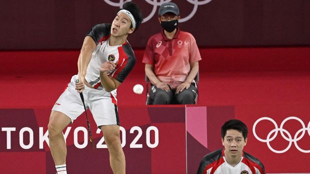 Indonesia's Marcus Fernaldi Gideon (L) hits a shot next to Indonesia's Kevin Sanjaya Sukamuljo in their men's doubles badminton group stage match against India's Chirag Shetty and India's Satwiksairaj Rankireddy against during the Tokyo 2020 Olympic Games at the Musashino Forest Sports Plaza in Tokyo on July 26, 2021. (Photo by Alexander NEMENOV / AFP)