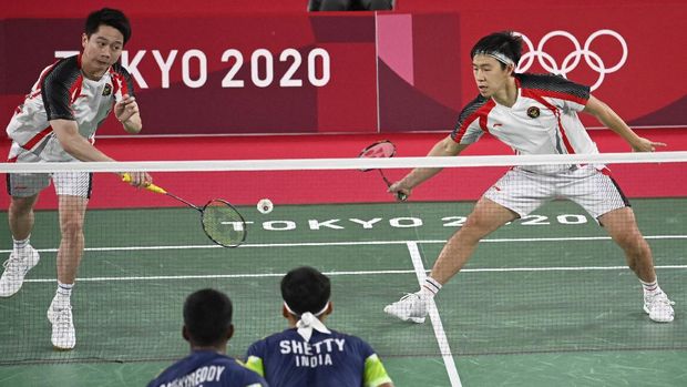 Indonesia's Marcus Fernaldi Gideon (R) watches Indonesia's Kevin Sanjaya Sukamuljo hit a shot in their men's doubles badminton group stage match against India's Chirag Shetty (bottom R) and India's Satwiksairaj Rankireddy during the Tokyo 2020 Olympic Games at the Musashino Forest Sports Plaza in Tokyo on July 26, 2021. (Photo by Alexander NEMENOV / AFP)