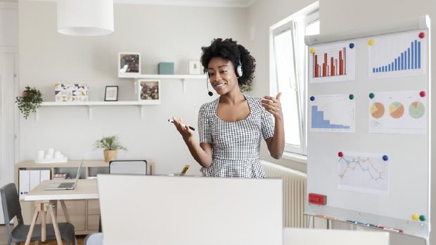 Dark Skinned Young Woman is Conducts Online Webinars, Online Classes, Online Presentation. African Girl Explains Something on a Flip-chart in an Office Classroom to Virtual Audience