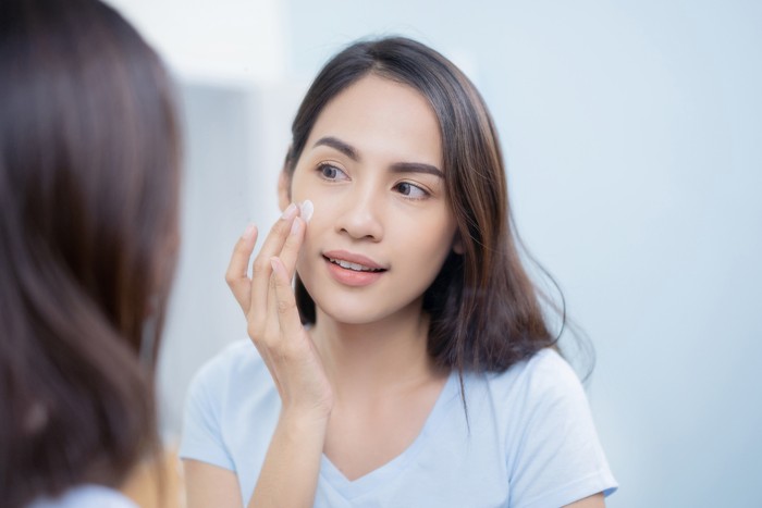 Asian women applying face lotion.