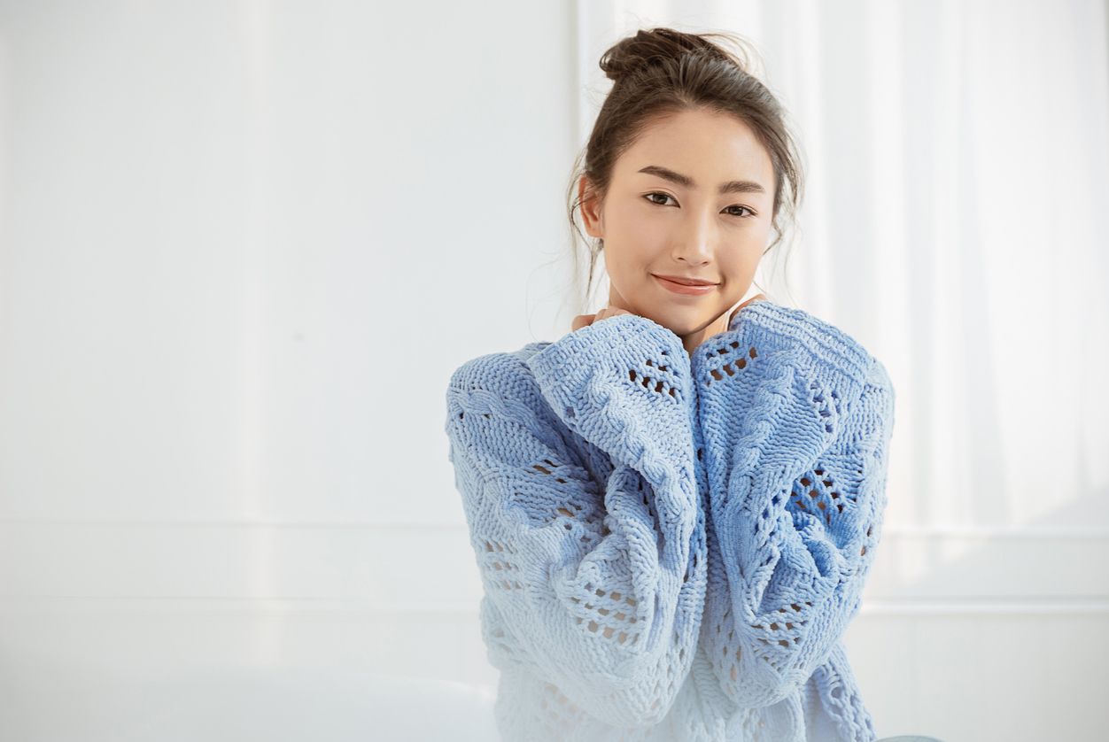 Portrait of young beautiful asian woman relax face in winter bedroom. Closeup sexy beauty fashion girl healthy makeup facial treatment perfect glow skin. Smile happy asia korean girl feel cold.