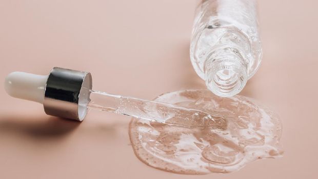 Bottle of hyaluronic acid on skin color background with oxygen bubbles. Selective focus