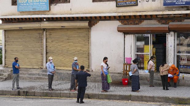 Local residents maintain social distancing as they stand in a queue to buy groceries outside a store during a nationwide lockdown imposed as a preventive measure against the spread of the COVID-19 coronavirus at Thimphu in Bhutan, on August 20, 2020. (Photo by Upasana DAHAL / AFP)
