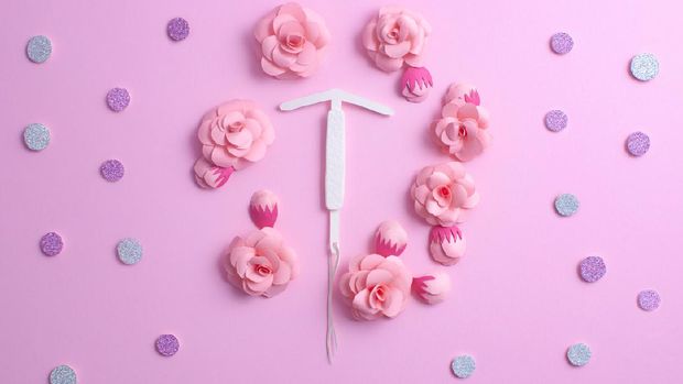 Concept hormonal contraception - pills, IUD, beautiful shiny tablets on a pink background, with paper flowers. Copy space for text