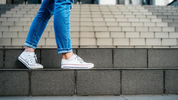 Young woman with backpack going down a staircase.