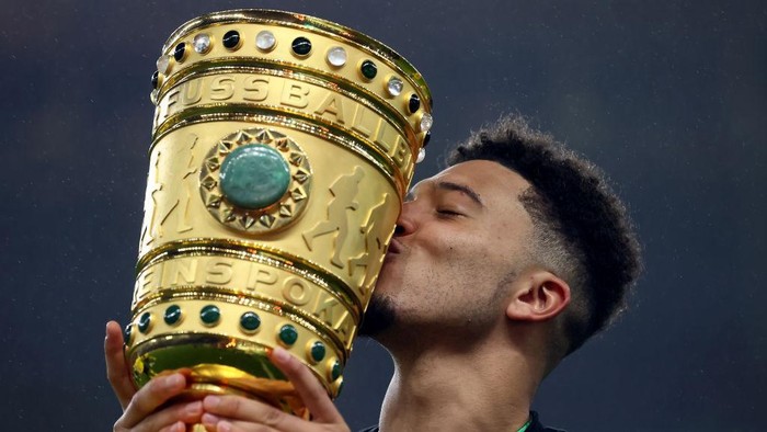 BERLIN, GERMANY - MAY 13: Jadon Sancho of Borussia Dortmund celebrates with the trophy after winning the DFB Cup final match between RB Leipzig and Borussia Dortmund at Olympic Stadium on May 13, 2021 in Berlin, Germany. Sporting stadiums around Germany remain under strict restrictions due to the Coronavirus Pandemic as Government social distancing laws prohibit fans inside venues resulting in games being played behind closed doors. (Photo by Martin Rose/Getty Images)
