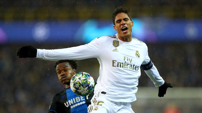 BRUGGE, BELGIUM - DECEMBER 11: Raphael Varane of Real Madrid is challenged by Percy Tau of Club Brugge during the UEFA Champions League group A match between Club Brugge KV and Real Madrid at Jan Breydel Stadium on December 11, 2019 in Brugge, Belgium. (Photo by Dean Mouhtaropoulos/Getty Images)