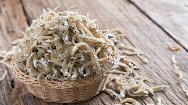 Raw anchovies over rustic wooden background