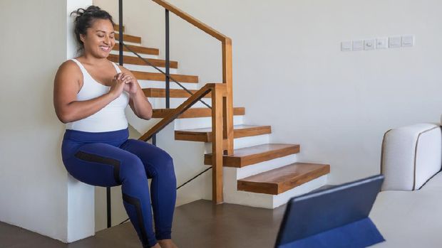 Portrait shot of an attractive Malaysian woman doing wall sit exercise in her living room during Covid 19 pandemic