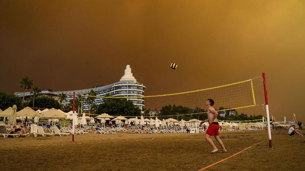 Kebakaran Hutan Mengamuk di Dekat Kawasan Resort Turki Dark smoke drifts over a hotel complex during a massive forest fire which engulfed a Mediterranean resort region on Turkey's southern coast near the town of Manavgat, on July 29, 2021. - At least three people were reported dead on July 29, 2021 and more than 100 injured as firefighters battled blazes engulfing a Mediterranean resort region on Turkey's southern coast. Officials also launched an investigation into suspicions that the fires that broke out Wednesday in four locations to the east of the tourist hotspot Antalya were the result of arson. (Photo by Ilyas AKENGIN / AFP)