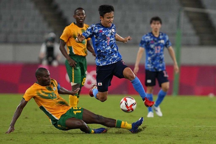 Tokyo Olympics Soccer Japan's Takefusa Kubo, leaps over Repo Malepe of South Africa during a men's soccer match at the 2020 Summer Olympics, Thursday, July 22, 2021, in Tokyo, Japan. (AP Photo/Shuji Kajiyama)