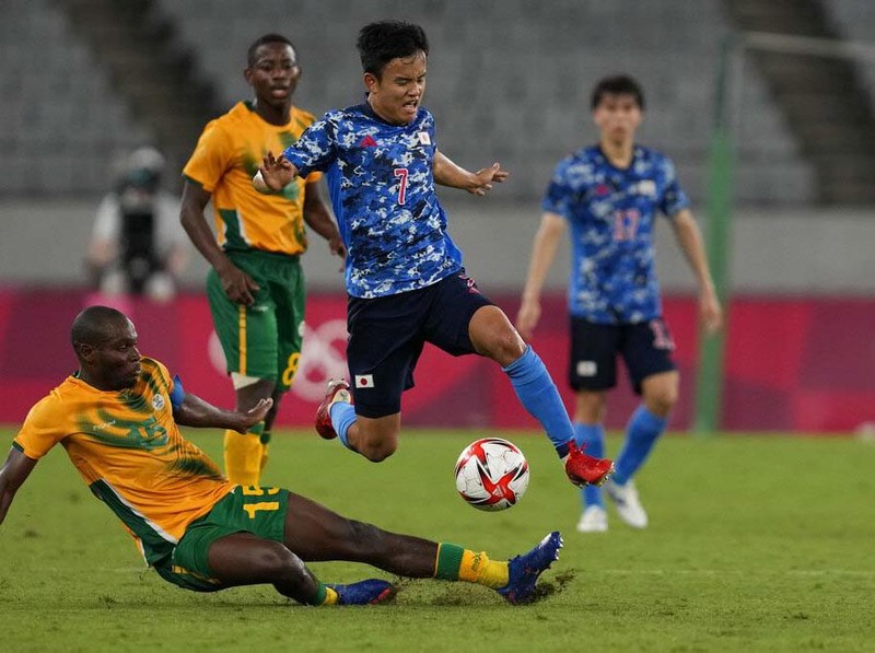 Japan's Takefusa Kubo, leaps over Repo Malepe of South Africa during a men's soccer match at the 2020 Summer Olympics, Thursday, July 22, 2021, in Tokyo, Japan. (AP Photo/Shuji Kajiyama)