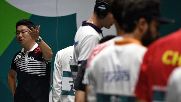 South Korea's Jin Jong-oh (L) argues during the men's 10m air pistol shooting final at the 2018 Asian Games in Palembang on August 21, 2018. (Photo by Mohd RASFAN / AFP)