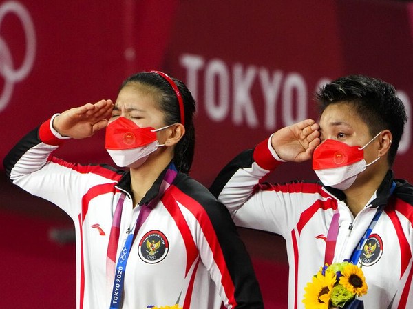 Gold medalists Greysia Polii, left, and Apriyani Rahayu from Indonesia listen to the national anthem during the medals ceremony of the womens doubles gold medal match at the 2020 Summer Olympics, Monday, Aug. 2, 2021, in Tokyo, Japan. (AP Photo/Markus Schreiber)