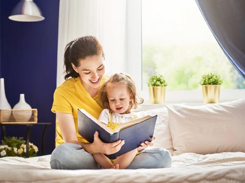 Pretty young mother reading a book to her daughter. Family holiday and togetherness.
