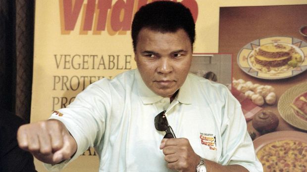 Boxing great Muhammad Ali throws a punch towards photographers during a press conference at a Jakarta hotel on October 21, 1996. Ali is in Indonesia to promote US food products by Vita-pro, and to donate to various Indonesian charities.   AFP PHOTO JOHN MACDOUGALL (Photo by JOHN MACDOUGALL / AFP)