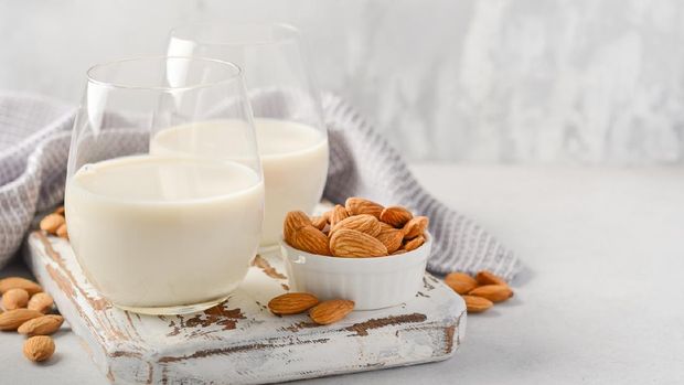 Almond milk and almonds on a white wooden cutting board, selective focus.