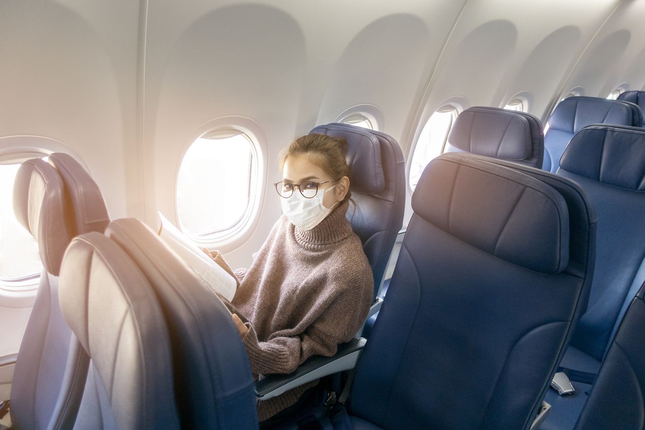 A young woman wearing face mask is traveling on airplane , New normal travel after covid-19 pandemic concept