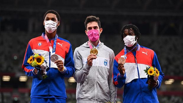 Tokyo 2020 Olympics - Athletics - Men's Long Jump - Medal Ceremony - Olympic Stadium, Tokyo, Japan - August 2, 2021. Gold medallist, Miltiadis Tentoglou of Greece poses on the podium with silver medallist, Juan Miguel Echevarria of Cuba and bronze medallist, Maykel Masso of Cuba as they all wear wearing protective face masks REUTERS/Dylan Martinez