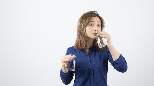 Young woman in blue blouse drinking glass of water. High quality photo