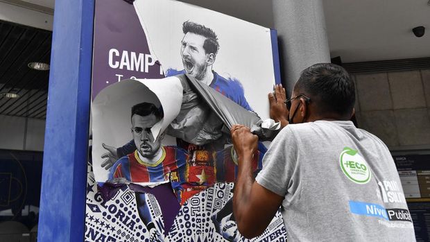 A worker removes posters featuring Barcelona's departing Argentinian forward Lionel Messi at the Camp Nou stadium in Barcelona on August 10, 2021. - France is waiting impatiently for Lionel Messi with supporters gathering outside Paris Saint-Germain's ground hoping to see the Argentine who is expected to join the Qatar-owned club after his exit from Barcelona. (Photo by Pau BARRENA / AFP)